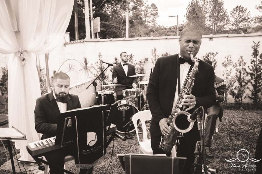 Saxofone, teclado e bateria tocando ao vivo em casamento ao ar livre